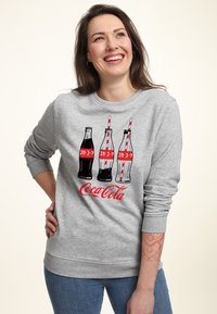 Felpa grigia con tre bottiglie di Coca-Cola classiche con etichette rosse e cannucce, arricchita da una grande scritta rossa "Coca-Cola" in basso.