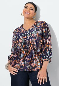 Bluse mit Blumenmuster in Dunkelblau mit orangen und grünen Akzenten, mit V-Ausschnitt, elastischem Taillenbund und drei Viertel Puffärmeln.