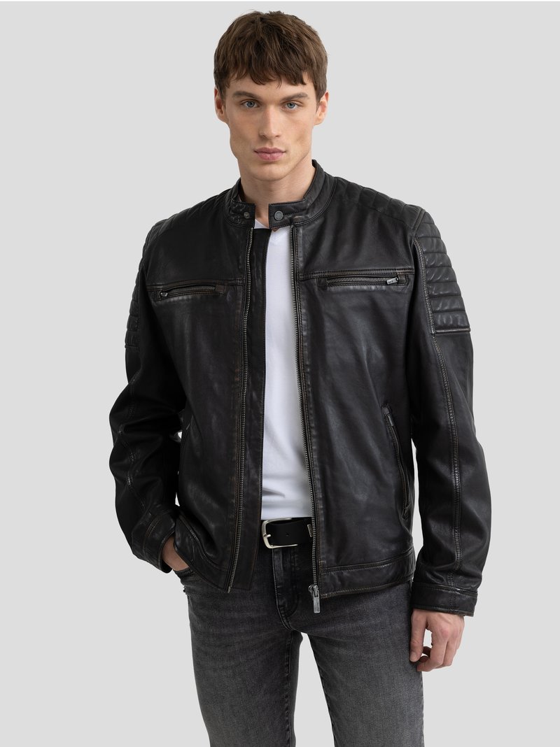 Jachetă din piele neagră, cu fermoar frontal, accente ribbate pe umeri și două buzunare cu fermoar pe piept. Purtați cu un tricou alb și blugi închiși.