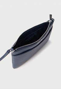Temno modra usnjena torbica z teksturirano zunanjostjo, srebrno kovinsko opremo in zadrgo za zapiranje. Notranjost ima gladko podlogo z logotipom.