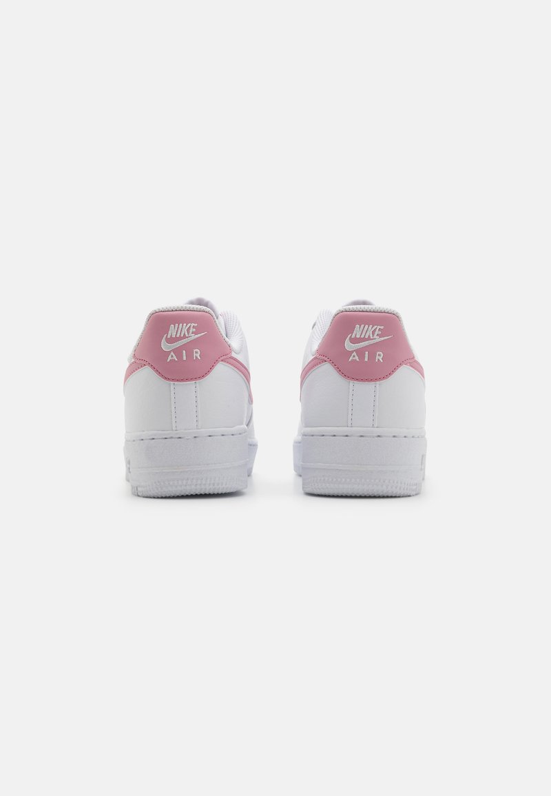Sneakers Nike Air bianchi con dettagli rosa sul tallone. Materiale in pelle liscia, suola piatta e cuciture bianche. Logo ben visibile.