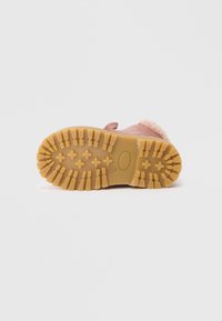 Bota infantil rosa com punho fofinho, sola de borracha texturizada com sulcos profundos para tração e um detalhe costurado na parte superior.
