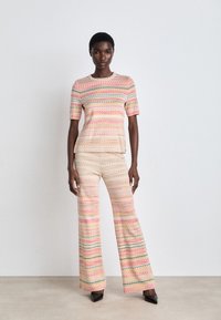 Multicolored knit two-piece set featuring a short-sleeve top and flared pants with a zigzag pattern in pink, yellow, and green hues.
