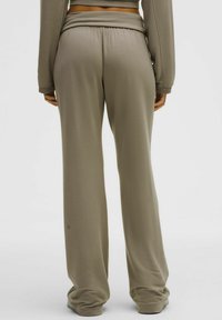 Világosbarna, laza szabású melegítőnadrág rugalmas derékkal és puha textúrával, amely a boka fölé ér és sima befejezéssel rendelkezik.