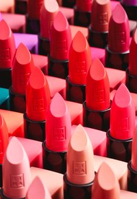 Leppestifter i forskjellige nyanser, inkludert rødt, rosa og nude, med glatte, runde tupp og matt finish i svarte sylinderformede tilfeller.