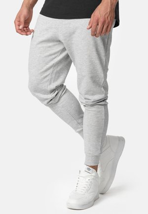 Grå bomulds joggingbukser med tætsiddende ben, elastiske manchetter og sidelommer, parret med hvide høje sneakers.