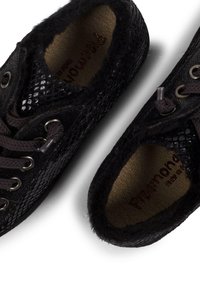 Schwarze Sneakers mit strukturiertem Schlangenhautmuster, weichem Fellfutter und braunen Schnürsenkeln. Das Innenfutter enthält eine beige Innensohle.