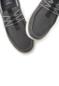 Graue Leinenschuhe mit strukturierter Oberfläche, kontrastierenden schwarzen und weißen Schnürsenkeln und einer hellen, leicht gefleckten Gummisohle.