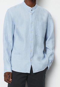 Vaaleansininen pellavapaita, jossa on kaulus, pitkät hihat, etunapit ja rintatasku. Rakenteellinen kangas, jossa on rento istuvuus.