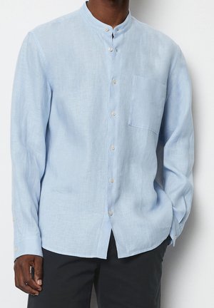 Camisa de lino azul claro con cuello tipo Mao, mangas largas, botones frontales y un bolsillo en el pecho. Tejido texturizado con un corte casual.