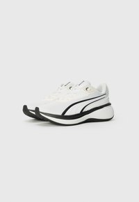 White athletic shoes with breathable mesh upper, black accents, thick cushioned sole, and contrasting striped design. Durable rubber outsole.