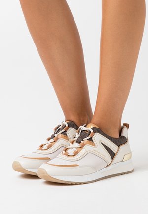 Zapatillas de cuero blanco y marrón con detalles de malla, diseño curvado, suela de goma y cordones marrones. Presentan una marca en el lateral.