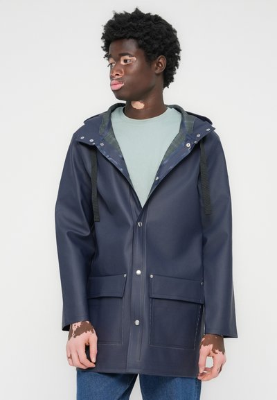 Marineblauer wasserdichter Mantel mit Kapuze, aus glattem Material, ausgestattet mit schwarzen Riemen, Druckknöpfen und vorderen Taschen.