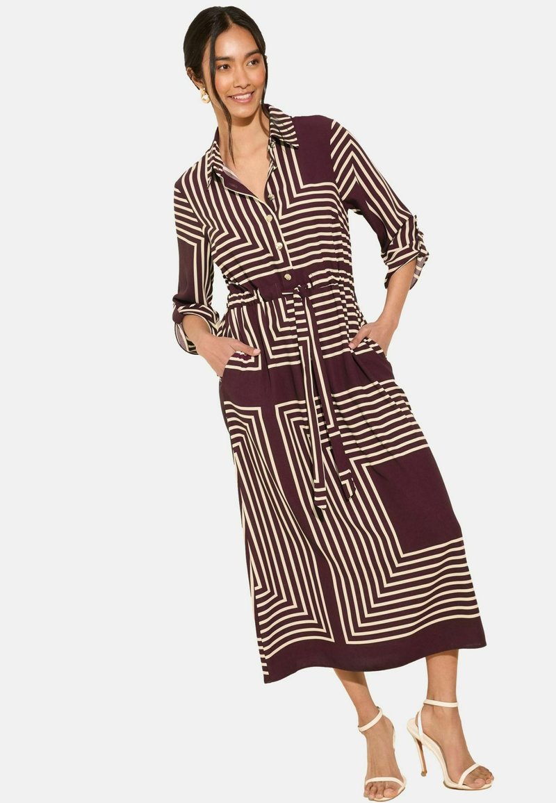 Tiefpurpurfarbenes midi-Kleid mit V-Ausschnitt und langen Ärmeln, verziert mit cremefarbenen geometrischen Streifen. Es hat einen Gürtel, eine Knopfblende und seitliche Taschen.
