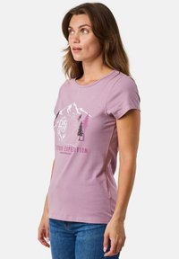 Lyse lilla T-shirt lavet af blød bomuld med rund hals, korte ærmer og et udendørs-tema grafik med bjerge, en løve og træer.