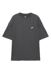 Tricou larg cu mâneci scurte, de culoare gri închis, cu un mic logo roz în partea superioară stângă a pieptului și decolteu rotund.