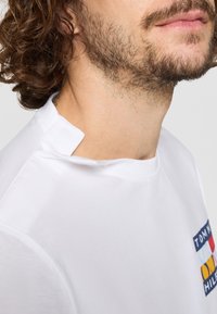 Hvid bomulds-T-shirt med rund halsudskæring, kortærmer og et farverigt logo-patch på venstre bryst. Teksturert, afslappet pasform.