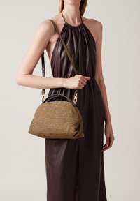 Brown textured handbag with a curved shape, a top handle, and a detachable strap. Detailed with gold-tone hardware and smooth leather accents.