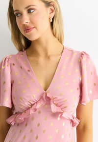 Pink dress with gold dot pattern, ruffled detailing at the bust and sleeves. Light, smooth fabric; V-neck design. Small button at neckline.