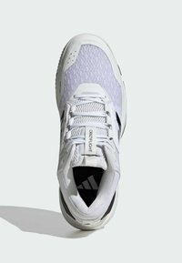 Białe buty sportowe z siateczki i materiałów syntetycznych, okrągłym noskiem, sznurowanym zapięciem oraz czarnym logo na wkładce.