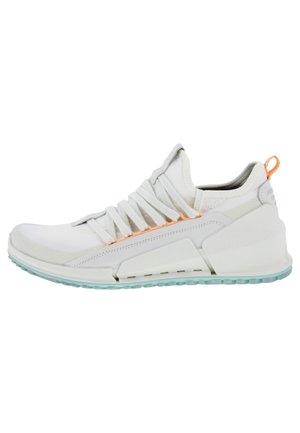 Baskets blanches de sport avec semelle épaisse, design angulé unique, col rembourré, languette orange et semelle extérieure bleu clair.