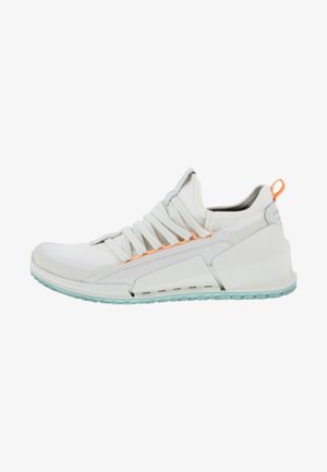 Biały sportowy sneaker z grubą podeszwą, unikalnym skośnym wzorem, wyściełanym kołnierzem, pomarańczową pętlą do ściągania i jasnoniebieskim bieżnikiem na spodzie.