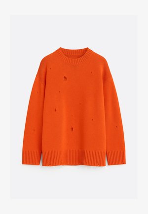 Ryškios oranžinės spalvos megztinis su apvalia iškirpte, briaunotais rankogaliais ir apačia, dekoruotas keliomis mažomis tikslingomis skylutėmis, suteikiančiomis sendinto dizaino efektą.