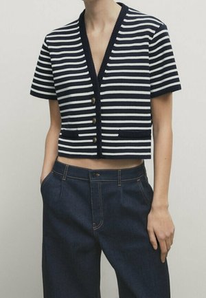Femme portant un cardigan court rayé bleu marine et blanc à manches courtes avec des boutons et un jean large taille haute bleu foncé.
