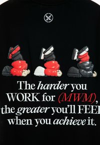 Camiseta de tela negra con figuras de dibujos animados bordadas en rojo, negro y blanco, junto con el texto motivacional en negrita blanca y roja.