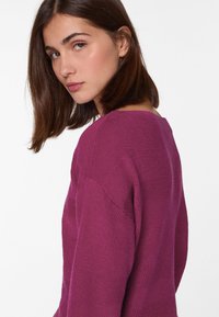 Angepasster, tiefvioletter Pullover mit gerippter Textur, weitem Halsausschnitt und subtilem geometrischem Muster an den Ärmeln und dem Körper.