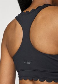 Μαύρο αθλητικό σουτιέν με σχέδιο κομμένης άκρης, υφασμάτινη υφή και στυλ racerback. Περιλαμβάνει το λογότυπο "Ted Baker Sport".