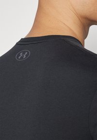 Camiseta atlética negra de manga corta, fabricada con una tela suave, que presenta un logo sutil en la parte trasera del cuello y costuras planas.