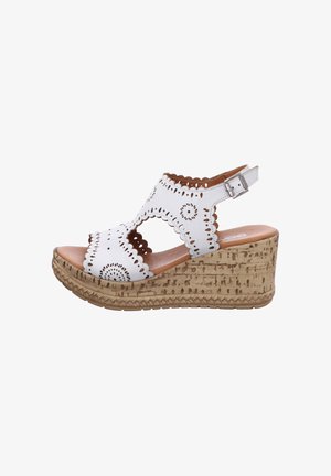 Weiße Espadrille Keilsandale mit perforiertem Blumendesign, braunem Lederfußbett und einer korktexturierten Sohle. Verstellbarer Knöchelriemen inklusive.