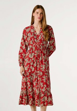 Rode bloemenjurk met lange mouwen, v-hals en een geglazen taille. Heeft een gelaagde rok en een crèmekleurig bloemenpatroon. Glad materiaal.