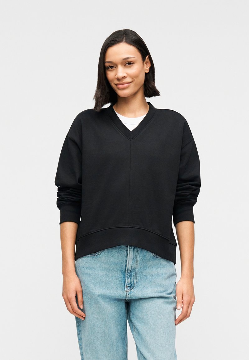 Μαύρο φούτερ με V-λαιμόκοψη, άνετη εφαρμογή και χαλαρούς ώμους. Κατασκευασμένο από απαλό υλικό, με ριμπ μανσέτες και καμπυλωτό τελείωμα.