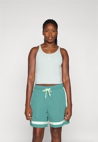 Top corto verde menta con un pequeño logo blanco, combinado con pantalones cortos de color teal que presentan rayas blancas y verdes y un cordón ajustable.