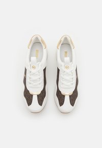 White and brown athletic shoes with mesh and leather material, featuring gold accents and laces, a rounded toe, and a textured sole.