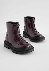 Bottines en cuir verni bordeaux avec des zips latéraux, semelles en caoutchouc noir et motifs antidérapants. Fini lisse avec des détails de couture contrastants.