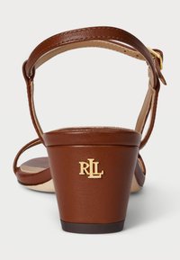 Pruunid nahk kõrge kontsaga sandaalid, millel on kaardus plokk-konts ja ühe rihmaga disain. Omab kuldset "RL" logo kontsal.