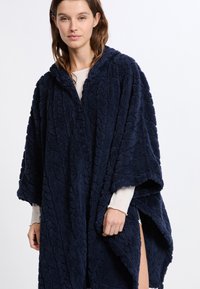 Poncho blu navy, morbido e con cappuccio, con design texturizzato e ampie aperture per le braccia. Il tessuto morbido si drappeggia liberamente per comfort e calore.