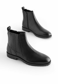 Stivali ankle in pelle nera con finitura liscia, pannelli laterali elasticizzati e linguetta posteriore per una facile calzata; suola in gomma piatta per aderenza.