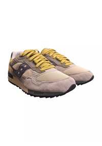 Sneaker caratterizzati da una combinazione di suede beige e mesh, lacci gialli e una suola in gomma nera con un design testurizzato e logo laterale.