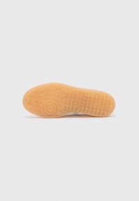 Rubber shoe sole with a honeycomb pattern, featuring circular and diamond textures. Color is translucent orange with a smooth finish.