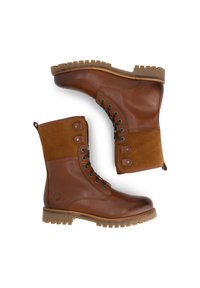 Bruine leren en suède veterschoenen met een stevige rubberen zool, zij oogjes en trekriempjes, zijaanzicht op een witte achtergrond.