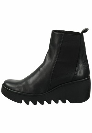 Black leather ankle boot with elastic side panels, rounded toe, and a thick, zigzag-patterned wedge sole. Features a pull tab for easy wear.