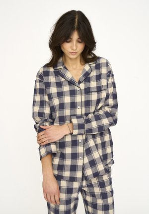 Plaid pyjamasæt bestående af en skjorte med knapper og matchende bukser. Fremstillet af blødt materiale i marineblå og cremefarvet ternet mønster, med en brystlomme.
