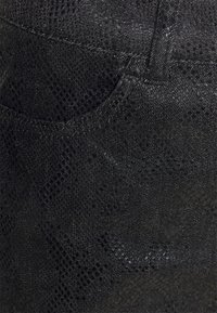 Černá texturovaná tkanina připomínající hadí kůži s jemným leskem. Obsahuje přední kapsu a složité vzory po celém povrchu.