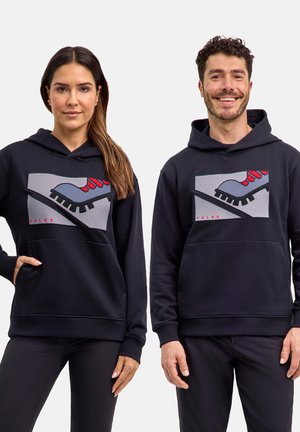 Deux adultes portant des sweat-shirts à capuche noirs assortis avec un graphisme d'une chaussure de randonnée grise et rouge sur la poitrine.