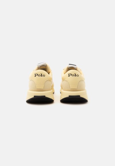 Paire de baskets Polo beige vues de dos avec semelles noires et marquage "Polo" sur les languettes de talon.