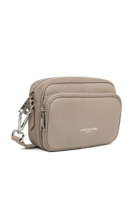 Borsa a tracolla in pelle beige con doppie tasche con zipper, hardware in argento e logo in rilievo "Lancaster Paris" sul davanti. Texture liscia.